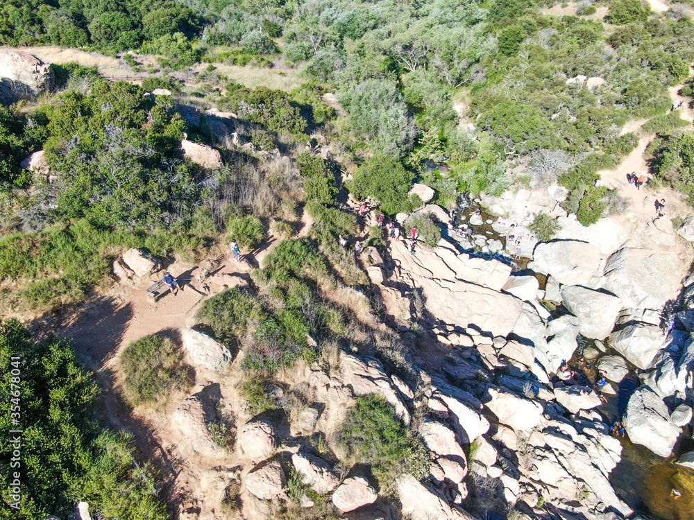 Fototapeta premium Aerial view of Los Penasquitos Canyon Preserve with the creek waterfall and people enjoying the water. Urban park with trails and river in San Diego, California. USA