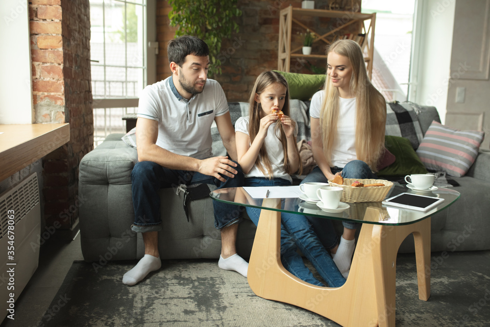 Mother, father and daughter at home having fun, comfort and cozy concept. Looks happy, cheerful and joyful. Beautiful caucasian family. Spending time together, drinking tea, eating croissant, icecream Mother, father and daughter at home having fun, comfort and cozy concept. Looks happy, cheerful and joyful. Beautiful caucasian family. Spending time together, drinking tea, eating croissant, icecream