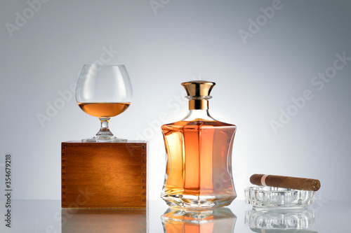 close up view of cigar, bottle of whiskey and a glass aside on grey back. 