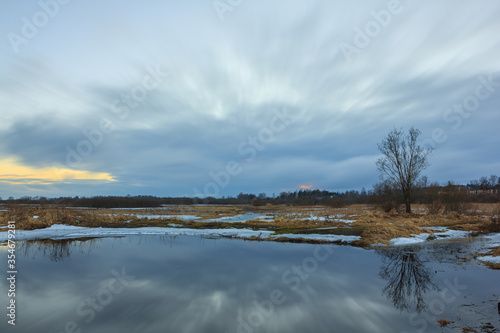 Beautiful evening sky with clouds and reflections in the water. Spring in the village © Александр Хализов