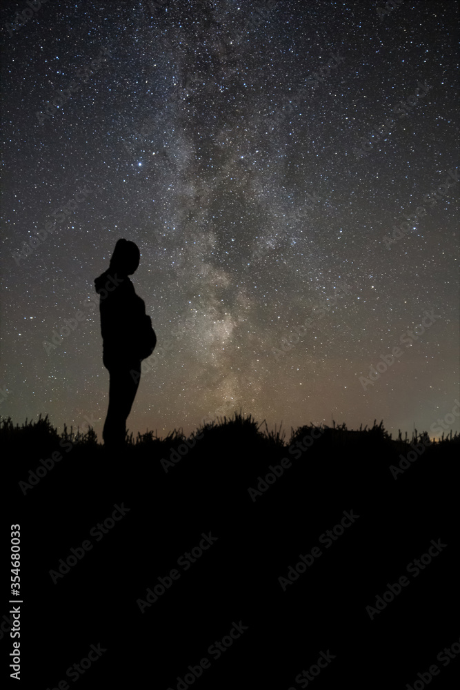 Pregnant woman standing on night sky. Silhouette on the field. Motherhood, pregnancy, happiness concept