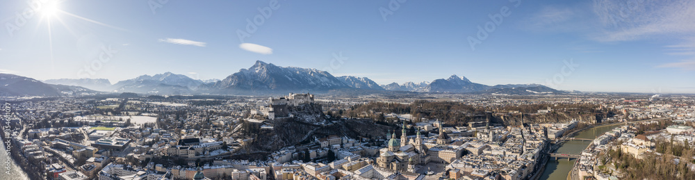 Fototapeta premium Panoramic aerial drone view of snowy Salzburg old town with river and Unesberg mountain in winter morning