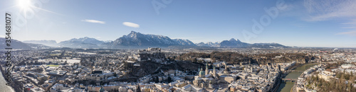 Panoramic aerial drone view of snowy Salzburg old town with river and Unesberg mountain in winter morning