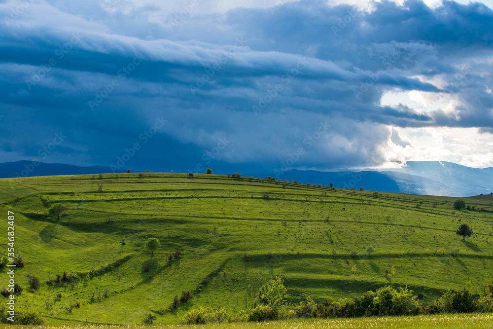 Gathering storm clouds over green hills in the Carpathian mountains, Romania.