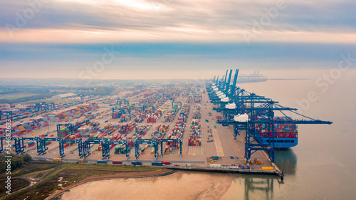 Aerial photograph of rows of stacked shipping containers and loading gantrys converging into the distance viewed hazily through the early morning mist. photo