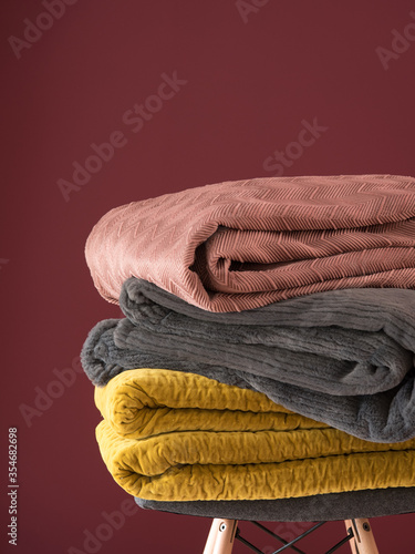 Folded Bed covers, blush textile, side view. Close-up of a stack or pile of colorful folded bed linen or duvet covers isolated on a red background. Macro.