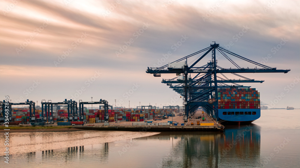 Aerial photograph looking through the line of loading gantrys in the early morning mist at Felixstowe container port. rows of stacked containers disappear into the distance early morning clouds streak Aerial photograph looking through the line of loading gantrys in the early morning mist at Felixstowe container port. rows of stacked containers disappear into the distance early morning clouds streak