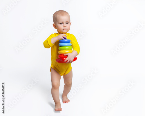 Canvastavla The baby is carrying a pyramid in her hands, walking barefoot on a white background
