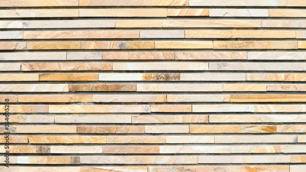 Decorative texture of a beautiful wall with rectangular parts made of multi-colored artificial stone. Collage of narrow granite blocks. Exterior finish with stone. Background from natural material. Decorative texture of a beautiful wall with rectangular parts made of multi-colored artificial stone. Collage of narrow granite blocks. Exterior finish with stone. Background from natural material.