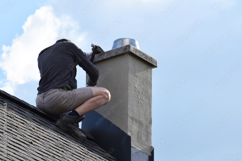 Roofer construction worker repairing chimney on grey slate shingles roof of domestic house, blue sky background with copy space.
 - obrazy, fototapety, plakaty 
