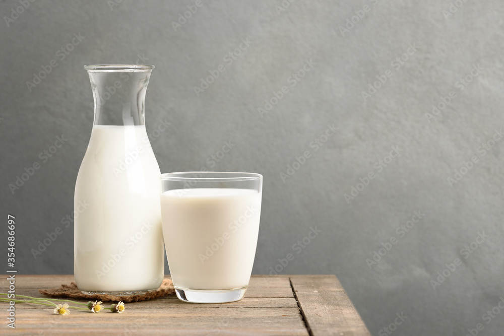 A glass and bottle of milk on wooden table with blur concrete wall background. A glass and bottle of milk on wooden table with blur concrete wall background.