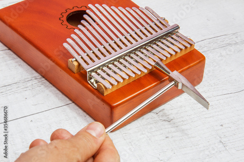 17-key Kalimba, ethnic plucked musical instrument.  A hand with a hammer  tuning this mbira. photo