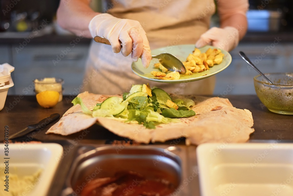 woman fills and rolls a vegetable wrap woman fills and rolls a vegetable wrap