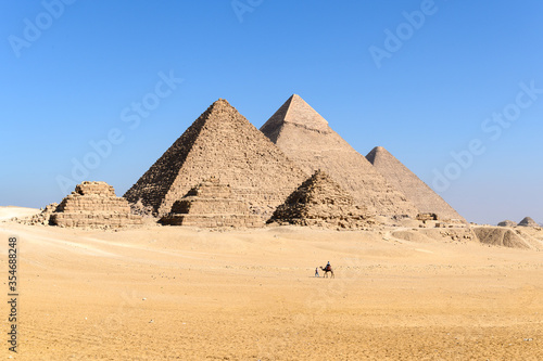 The great Pyramid complex of Giza with camel caravan walking through in front of the Egyptian pyramids- Giza- Cairo -Egypt