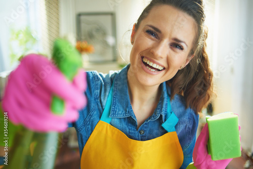 smiling woman with cleaning agent and sponge housecleaning photo