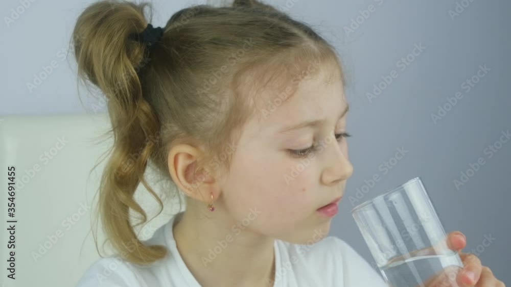 Caucasian girl child drinking water from a kitchen glass to stay hydrated during virus quarantine pandemic. Drink much water. Stay at home, slow motion 120fps Caucasian girl child drinking water from a kitchen glass to stay hydrated during virus quarantine pandemic. Drink much water. Stay at home, slow motion 120fps