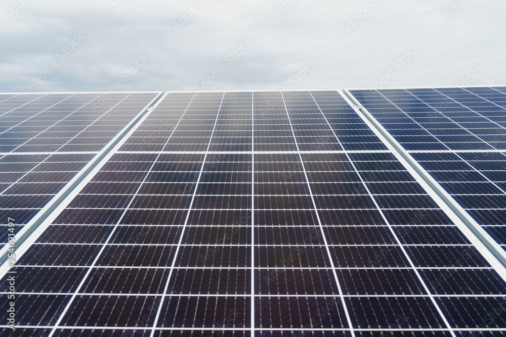 Solar cells closeup. Alternative solar panels power plant. Sustainability of planet. Green energy for home. Sun blue electric modules stands in row on the ground Solar cells closeup. Alternative solar panels power plant. Sustainability of planet. Green energy for home. Sun blue electric modules stands in row on the ground