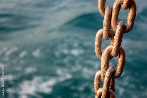 Chain and the sea. Chain close-up on the background of the sea at sunset. Sea waves in the evening out of focus.