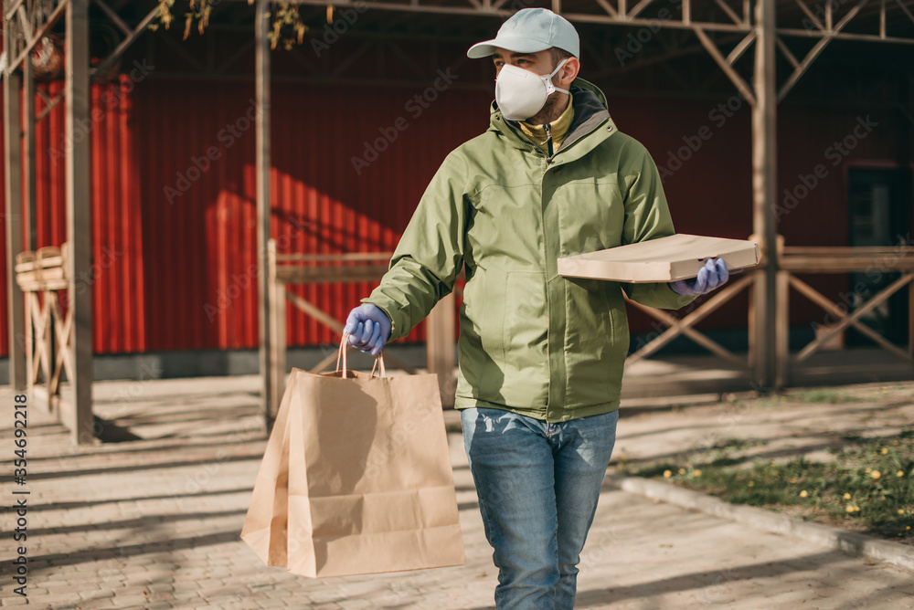 delivery man in medical mask and gloves delivers pizza from a restaurant. Quarantine, coronavirus, food delivery.