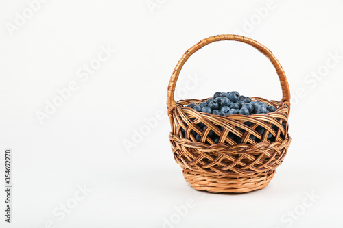 blueberry berries in wicker basket on white background with copy space