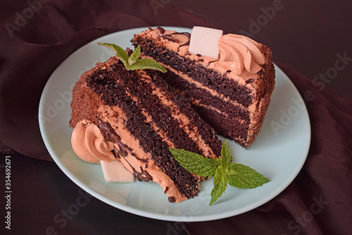 Delicious chocolate cake with cream filling and a sprig of mint on a plate.