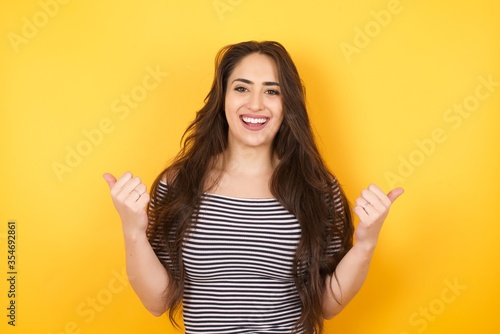 Closeup of young optimistic female isolated on grey background showing thumbs up with positive emotions of content and happiness. Copyspace, concept of satisfaction with quality and recommendation.