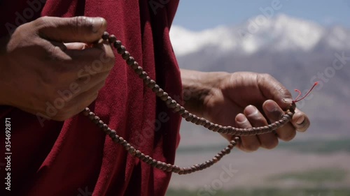 Buddhist debate and examination, hands of a monk with a rosary on the background of snowy mountains in Tibet