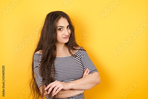 Waist up shot of beautiful self confident cheerful young woman entrepreneur has broad smile, crosses arms, happy to meet with colleague, dressed in fashionable clothes.