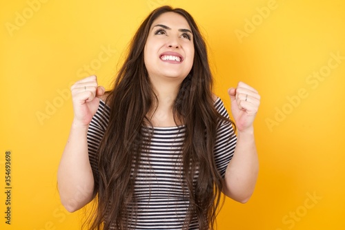 Excited Young woman winner raising his fists with great happiness having good mood after winning game. Young champion having success being glad to achieve her goals. Victory and triumph concept.