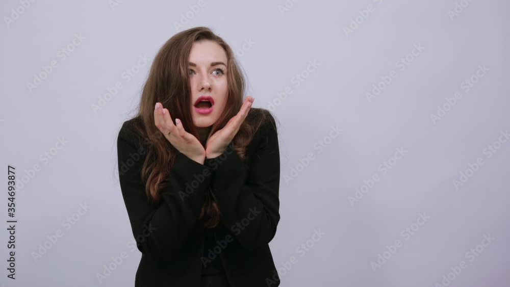 Young Attractive Woman Brunette In In A Black T-Shirt, Sweater On White Background, Confused Female Holds Face With Her Hands, Looks Surprised. Concept Shock And Suddenness Of People Young Attractive Woman Brunette In In A Black T-Shirt, Sweater On White Background, Confused Female Holds Face With Her Hands, Looks Surprised. Concept Shock And Suddenness Of People