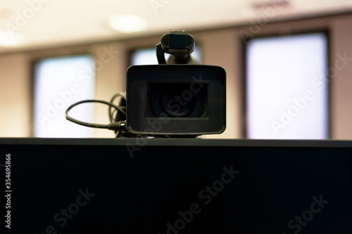 Fotografi Professional modern video camera above a blank monitor screen closeup, frontal shot