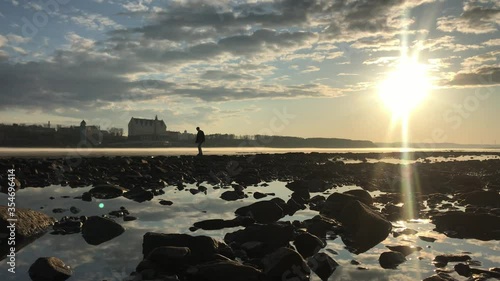 Sunset over the river. Very picturesque landscape. A man walks along the deserted shore with his dog. Evening fog floats over the river. On the other side of the river is a mansion.