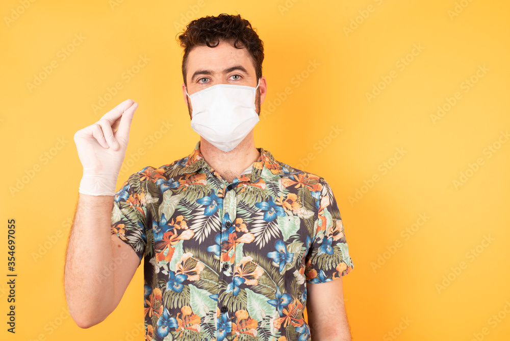 Handsome young businessman wearing hawaiian shirt and medical mask pointing up with hand showing up seven fingers gesture in Chinese sign language QÄ«. Handsome young businessman wearing hawaiian shirt and medical mask pointing up with hand showing up seven fingers gesture in Chinese sign language QÄ«.