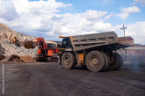 mining truck goes to the excavator for loading ore. Loading iron ore into a dump truck