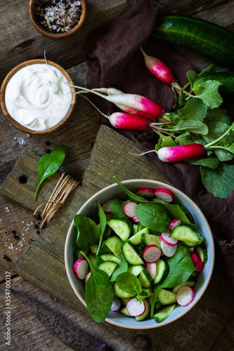 Healthy vegan food. Vegetarian vegetable salad of spinach, radish and fresh cucumber. Top view flat lay background.