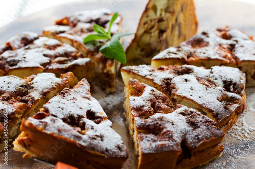 Authentic sponge cake with raisins, cinnamon and apples. Morning atmospheric lighting, fashionable trendy spot soft focus. Preparation for design creative menu. Culinary pastries.
