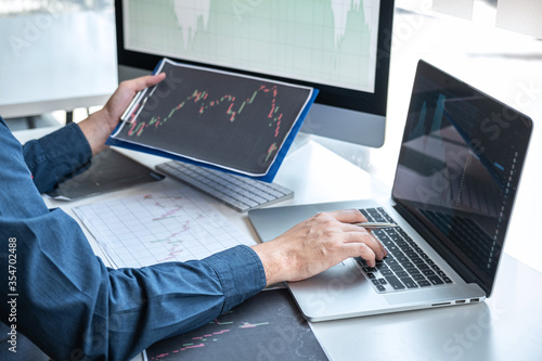 Stock exchange market concept, stock broker looking at graph working and analyzing with display screen, pointing on the data presented and deal on a exchange, Businessman trading stocks online