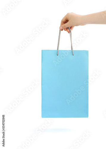Light blue paper bag for shopping in hand. Isolated on white background.