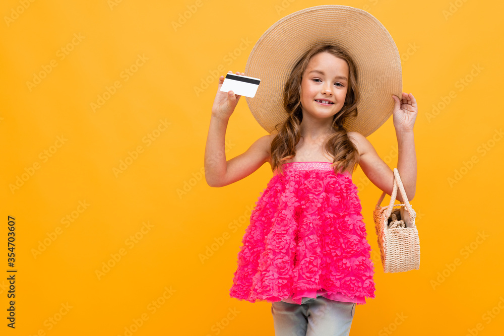 caucasian girl in a straw hat with a round bag holds a credit card with a mock up on a yellow background caucasian girl in a straw hat with a round bag holds a credit card with a mock up on a yellow background