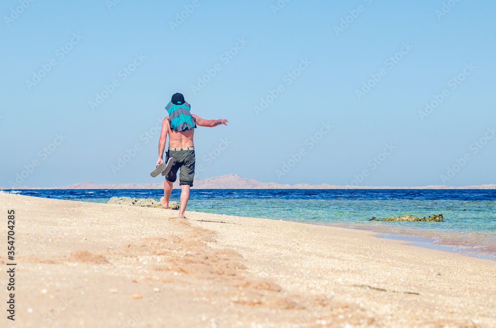 Barefoot man walks along the sandy sea coast