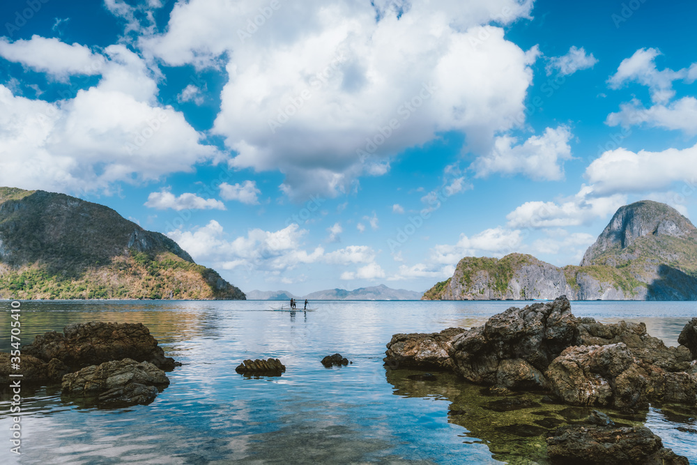 Palawan, Philippines. Seascape of El Nido bay, with white clouds, ocean reflection and Cadlao island in background