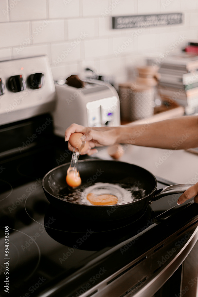 Breakfast preparation. Making morning meal. Weekday routine. Cooking food before work for family. Cracking the eggs into the pan. Home lifestyle. Brunch with husband. Stove, toaster. Selective focus