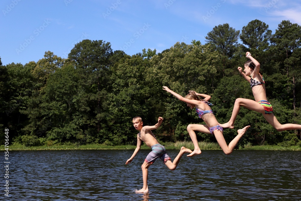 Three kids celebrating summer by jumping into the lake