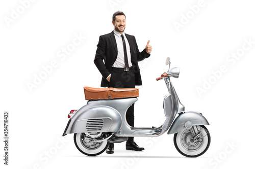 Businessman posing with a vintage silver scooter and showing thumbs up