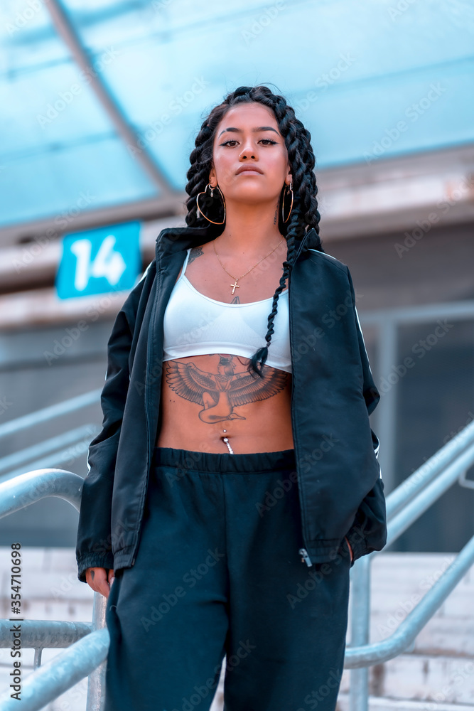 Obraz premium Urban session to trap dancer, with a young brunette of Latin ethnicity with braids, with unbuttoned black sweatshirt