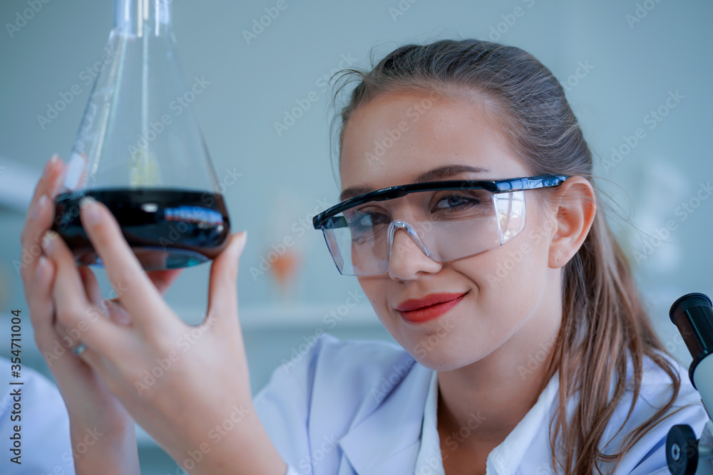 young caucasian medical scientist wearing protective glasses looked at the test tube containing sample for virus vaccination sample in test tube in a  laboratory