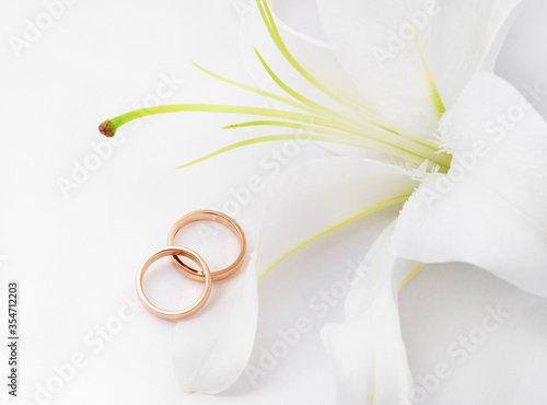 Gold wedding rings near white lily
