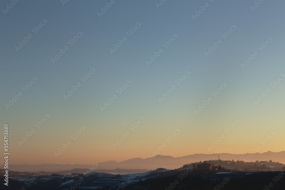 Winter landscape of the  hills and vineyards , sprinkle with snow at sunset, around Barolo Village, famous for the  fine wine, The Langhe area, Piedmont Italy.