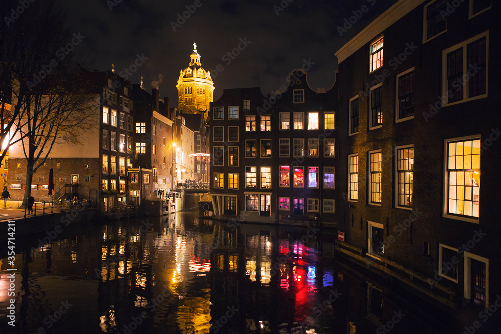Night view of Amsterdam city with the canal and Basilica of Saint Nicholas illuminated,  view from the Armbrug bridge, landmark of Netherlands, Holland, Europe.