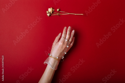 Fashion art hand woman in the glove with Jewelry in summer time and flowers behind her hand with bright contrasting makeup. Creative beauty photo hand skincare